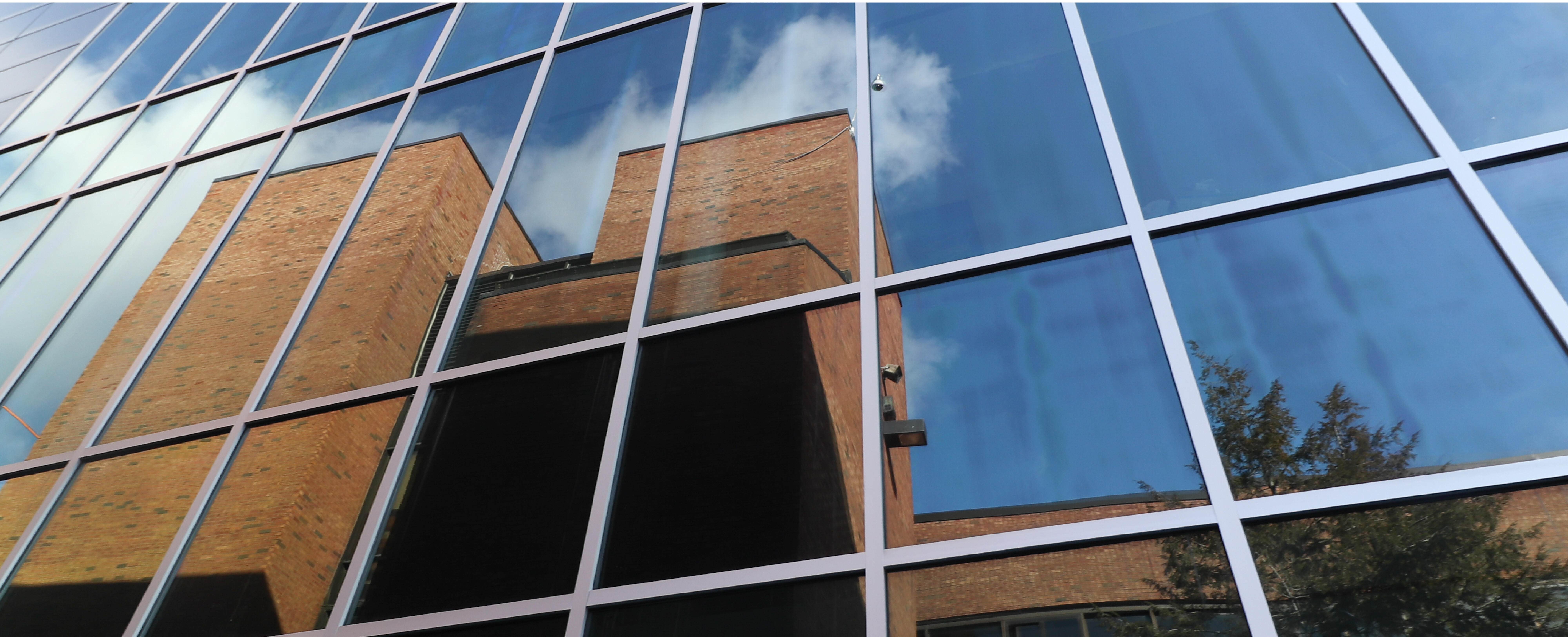Photo of old 33Ƶ High reflected in the glass of the new academic building